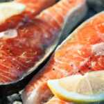 Heart healthy grilled salmon fillets with lemon herbs and olive oil on grill