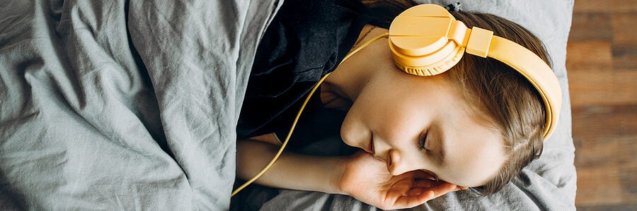 a child sleeping in bed with headphones on