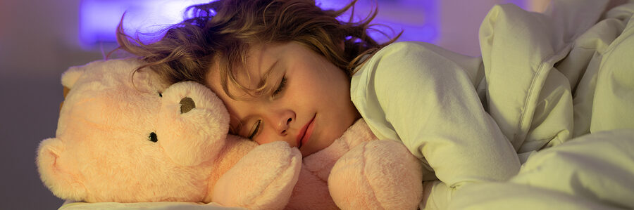 a child sleeping with a teddy bear