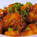 Heart healthy General Tso cauliflower florets in sauce served over brown rice with sesame seeds and green onions